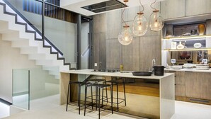 Une cuisine moderne dotée d’un îlot central, de tabourets de bar et de luminaires suspendus.