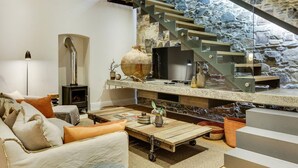 Un salon moderne avec un mur en pierre, un escalier en bois et une cheminée.