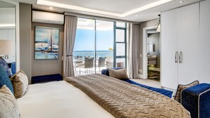 A modern hotel room with a large bed, a balcony with a view of the sea, a painting on the wall, and a wardrobe. - Stylish Secure Camps Bay Holiday Apartment 9 Nautica (Cape Town)