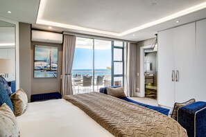Et moderne hotelværelse med en stor seng, en balkon med havudsigt, et billede på væggen og et garderobeskab.