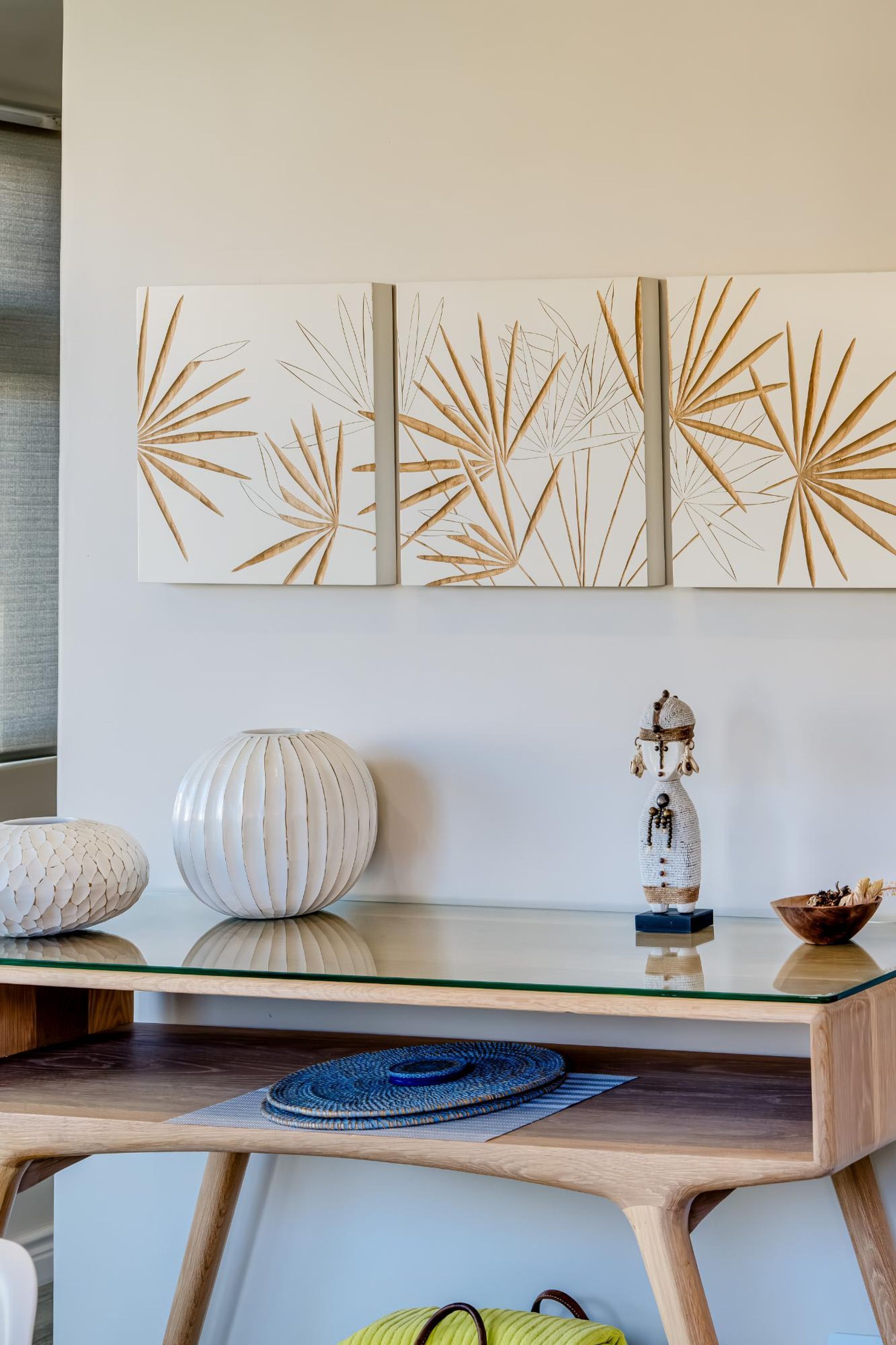 A modern interior with a glass-top table, decorative vases, and wall art.