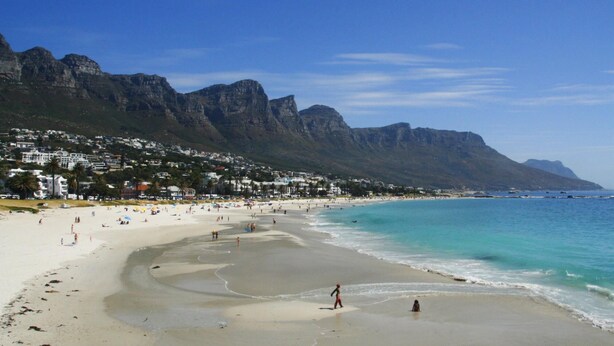 A beach with a mountain backdrop, clear skies, and a sandy shore. - Stylish 2 Bedroom Apartment in Camps Bay Asilvertide (Cape Town)