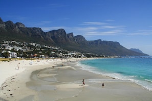 A beach with a mountain backdrop, clear skies, and a sandy shore. - Stylish 2 Bedroom Apartment in Camps Bay Asilvertide (Cape Town)