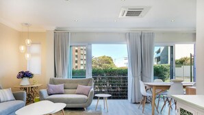 A modern living room with a sofa, coffee table, and dining area. - Stylish 2 Bedroom Apartment in Camps Bay Asilvertide (Cape Town)