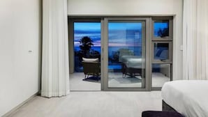 Een moderne hotelkamer met balkon, bed, bureau en stoel.