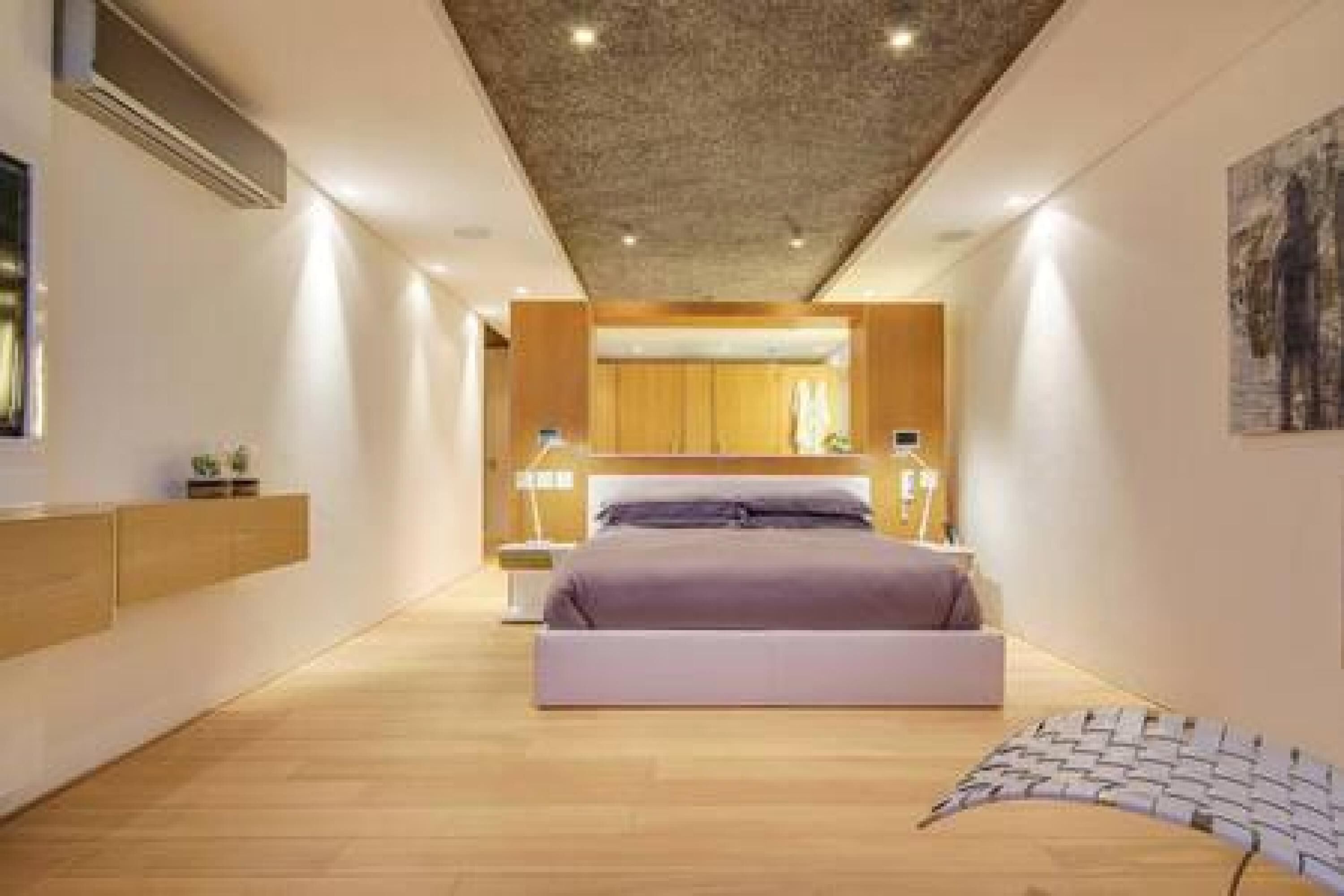 A modern bedroom with a bed, bedside tables, and a wooden floor.