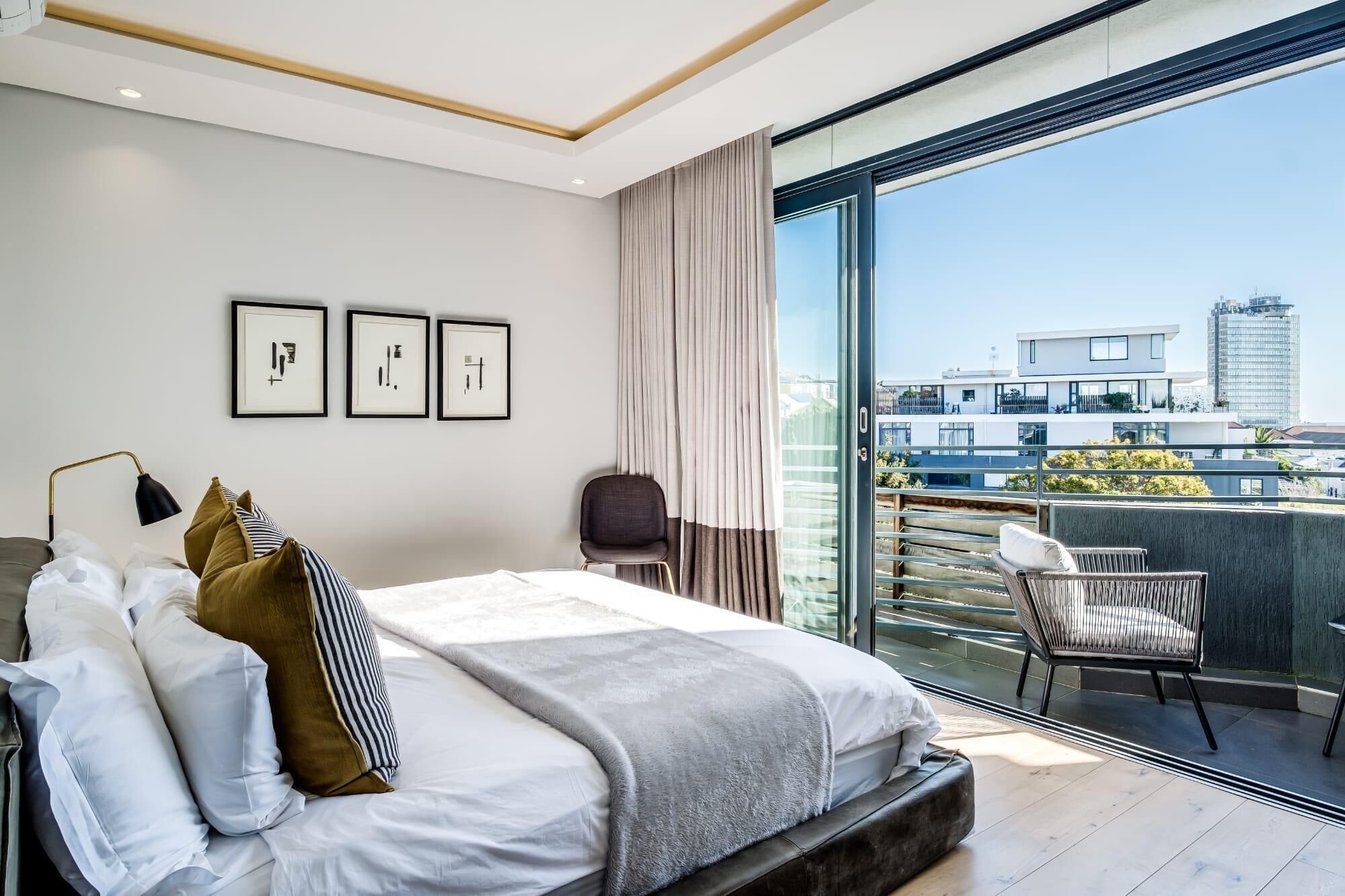 Un dormitorio moderno con una cama grande, un escritorio y vistas a un paisaje urbano.