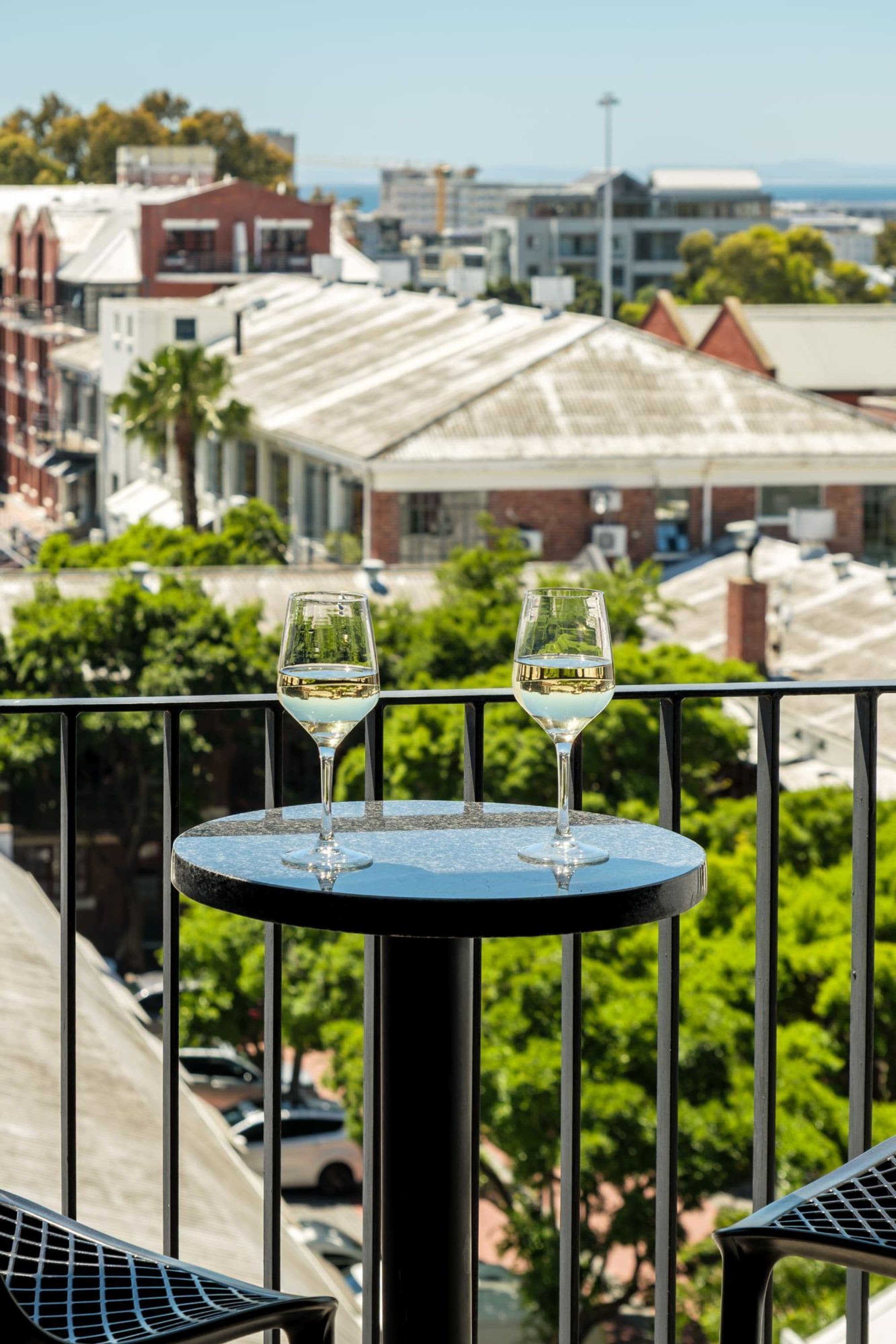 Deux verres de vin blanc sont posés sur une table ronde, avec en arrière-plan une vue sur le paysage urbain.