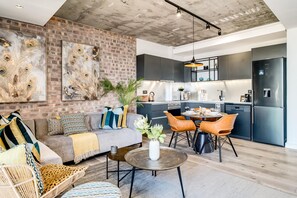 Ein moderner Wohnbereich mit Backsteinwand, einer Couch, einem Couchtisch und einem Essbereich mit Stühlen.