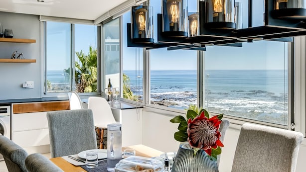 Espaço de refeições moderno com uma mesa posta para dois, com vista para uma praia.