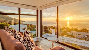 A modern room with large windows offering a sunset view over a coastal landscape. - Camps Bay Holiday Villa With Sunset Views Sunset Views (Cape Town)