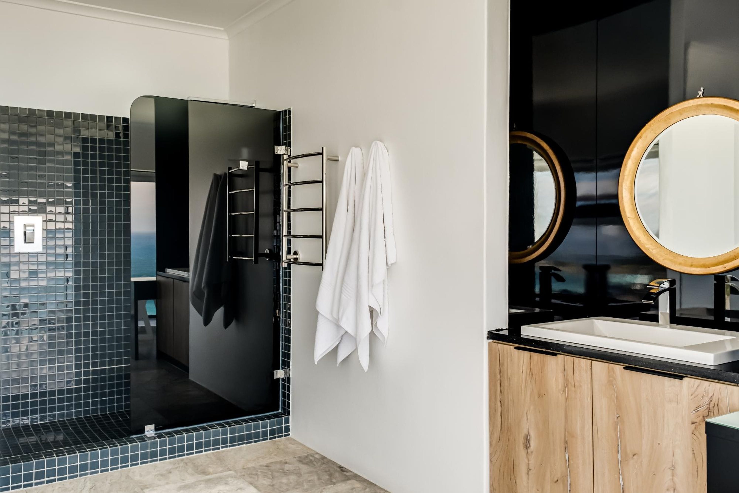 A modern bathroom with a glass shower enclosure, a wooden vanity, and a large mirror.