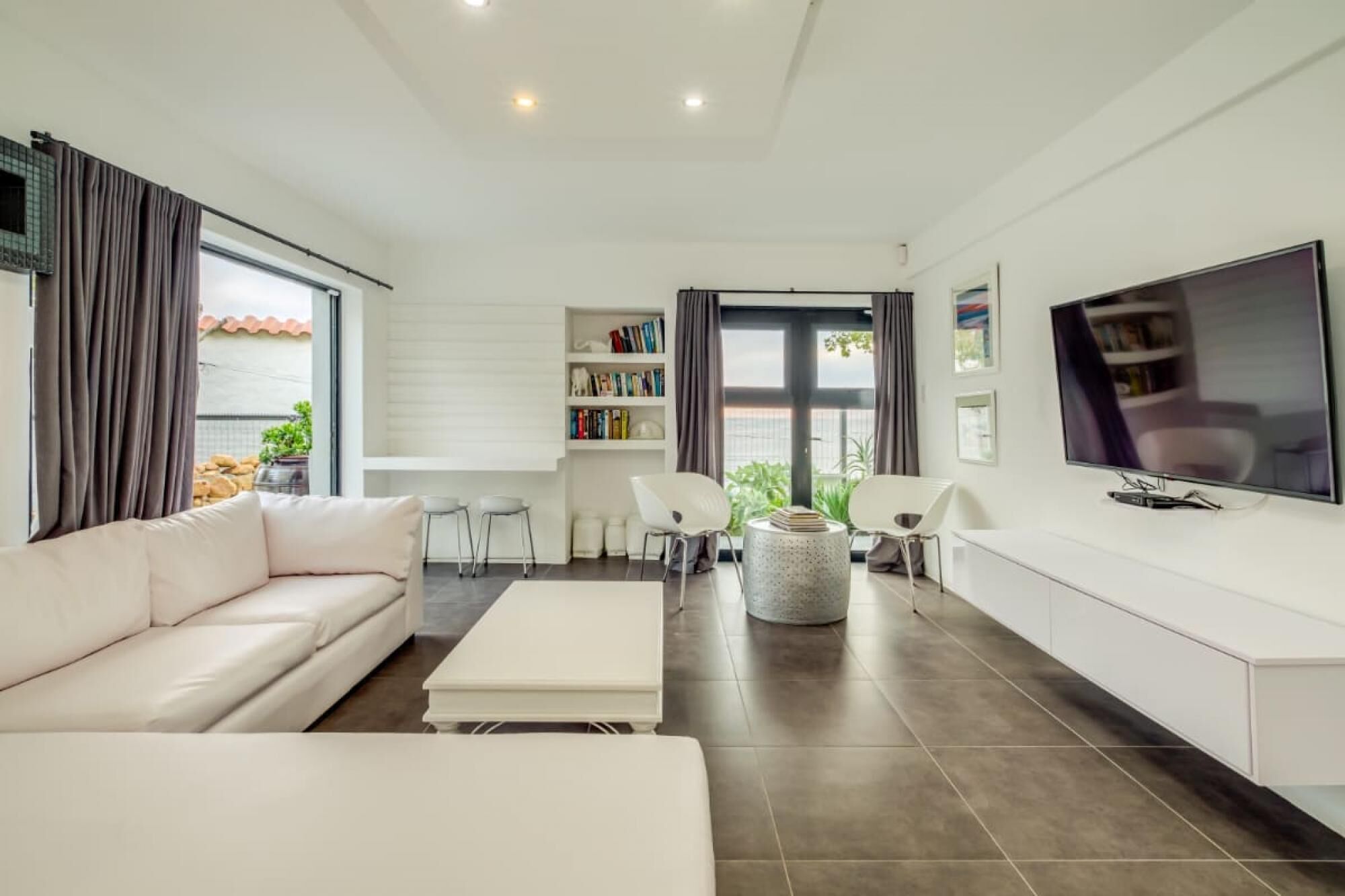 Una sala de estar moderna con un sofá, una mesa de centro, un televisor y una estantería.