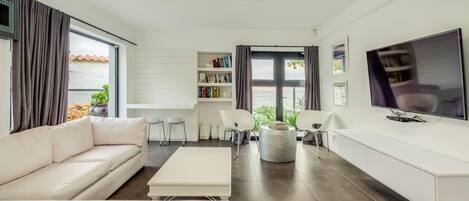 Una sala de estar moderna con un sofá, una mesa de centro, un televisor y una estantería.