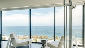 A modern bathroom with a large bathtub, two white chairs, and a view of the ocean. - Camps Bay Holiday Villa With Sunset Views Sunset Views (Cape Town)