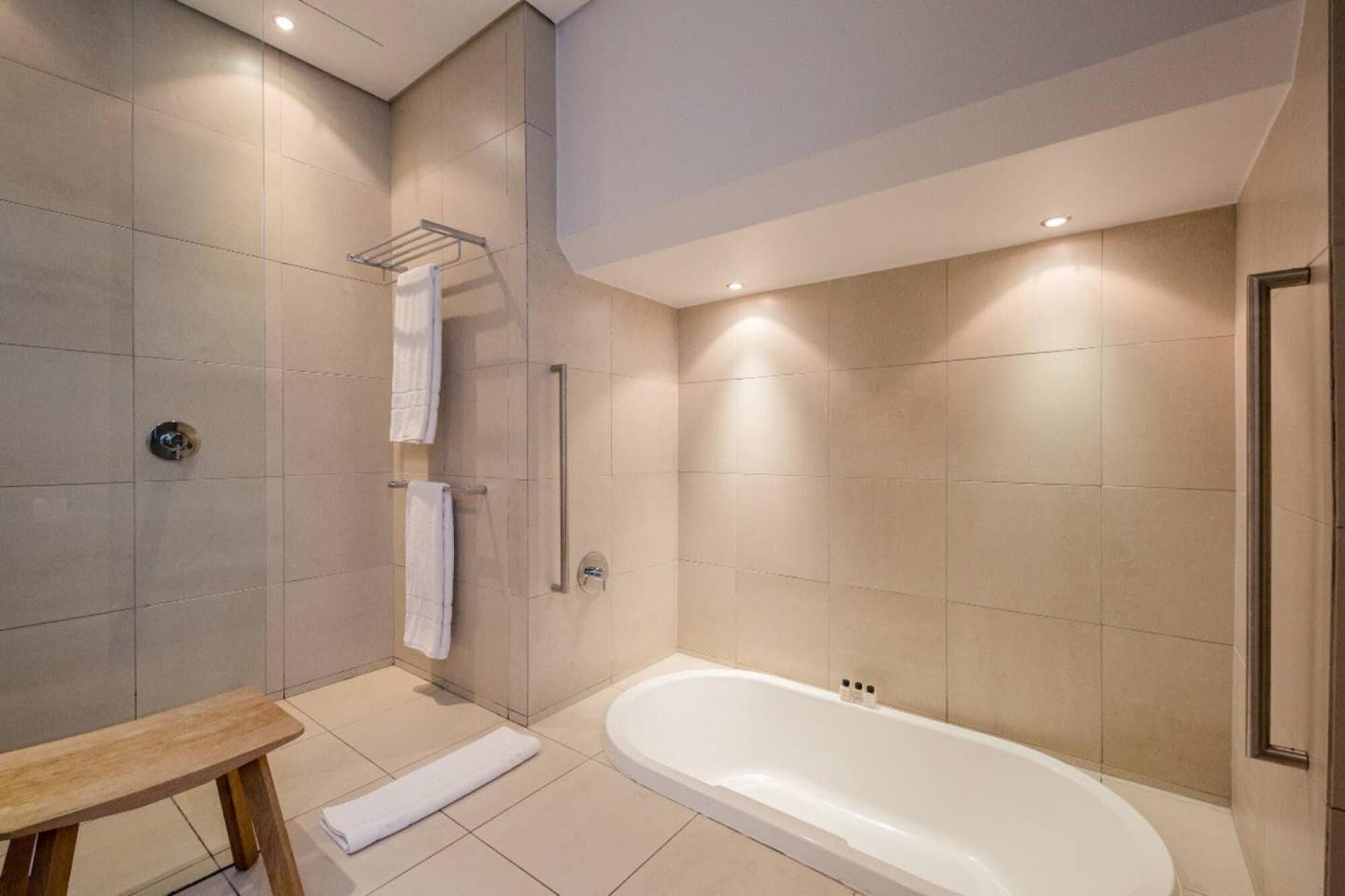 A modern bathroom with a bathtub, a shower, and a bench.
