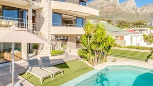 Uma casa moderna de dois andares com piscina, fachada de pedra e vista para as montanhas.