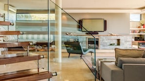 Uma sala de estar moderna com escada, lareira e um quadro grande.