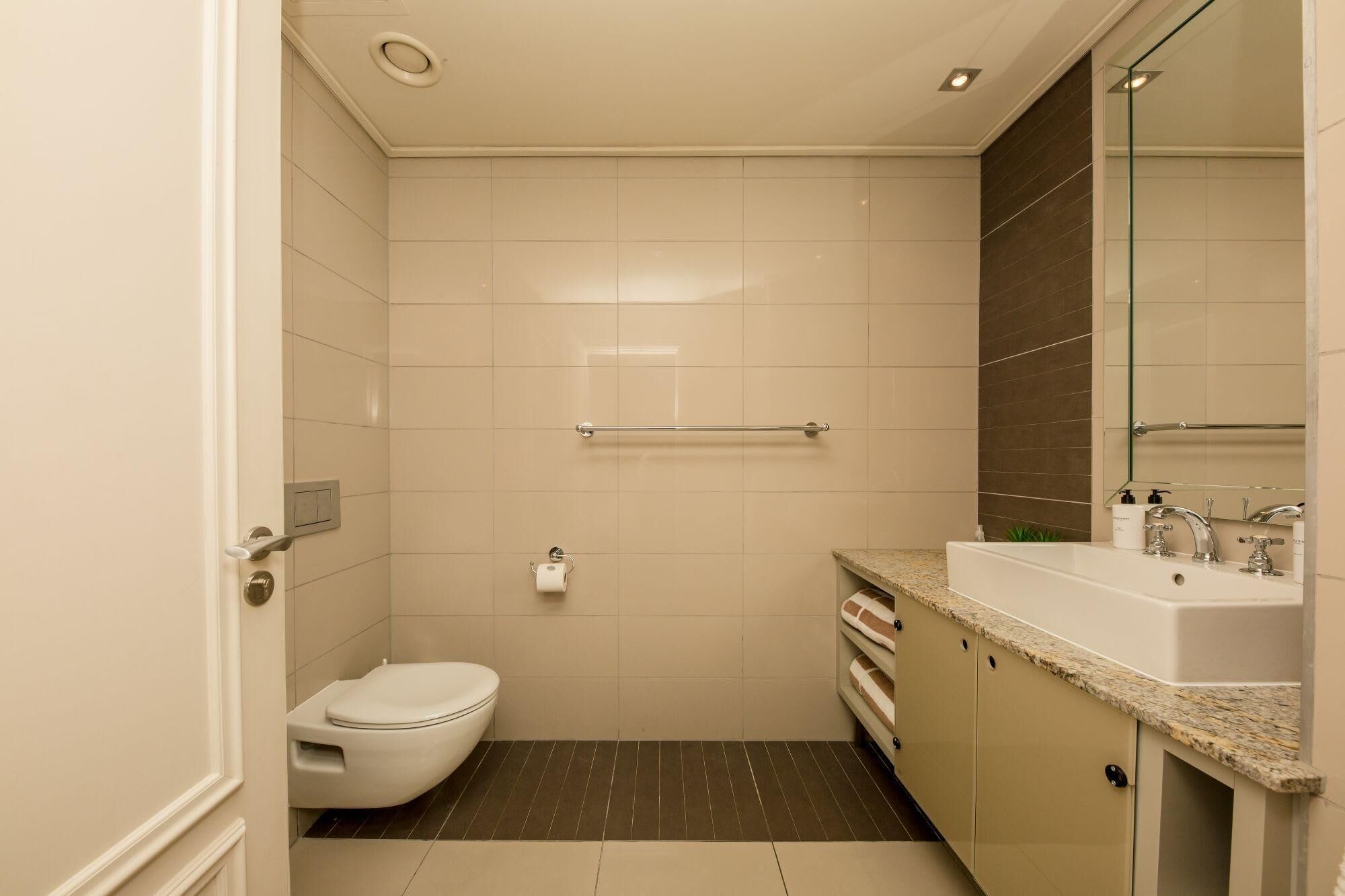Une salle de bain moderne avec des toilettes, un lavabo et un miroir.