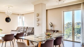A modern dining area with a glass table, cushioned chairs, a sofa, and a balcony with a view. - Green Point Apartment Walking Distance to Stadium 407 Royal (Cape Town)