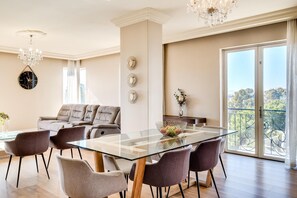 A modern dining area with a glass table, cushioned chairs, a sofa, and a balcony with a view. - Green Point Apartment Walking Distance to Stadium 407 Royal (Cape Town)