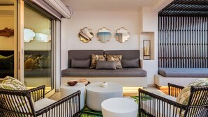 A modern living room with a grey sofa, round white side tables, and black wicker chairs. - Stylish Holiday Apartment w Private Pool 180 Views Malibu (Cape Town)