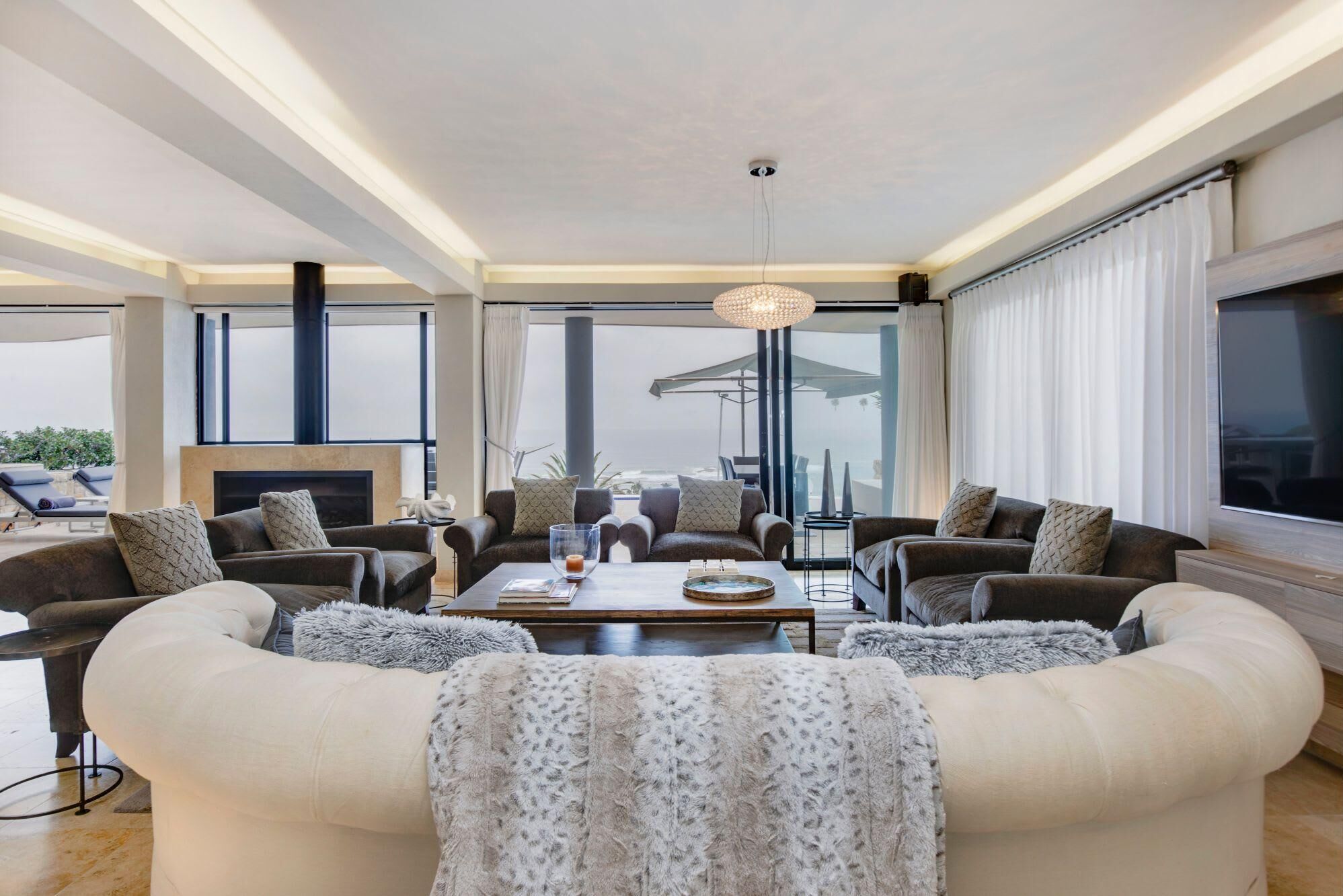 A modern living room with a fireplace, comfortable seating, and large windows offering a view.