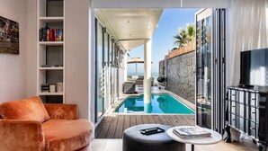 A modern living room with a pool, a sofa, a table, and a TV. - Beautiful 3bedroom Seaside Apartment Paloma Apartment (Cape Town)