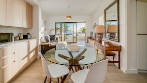 A modern kitchen with a glass dining table, white chairs, and wooden cabinets. - Beautiful Lock up go w Ocean Views Sundowner Views (Cape Town)