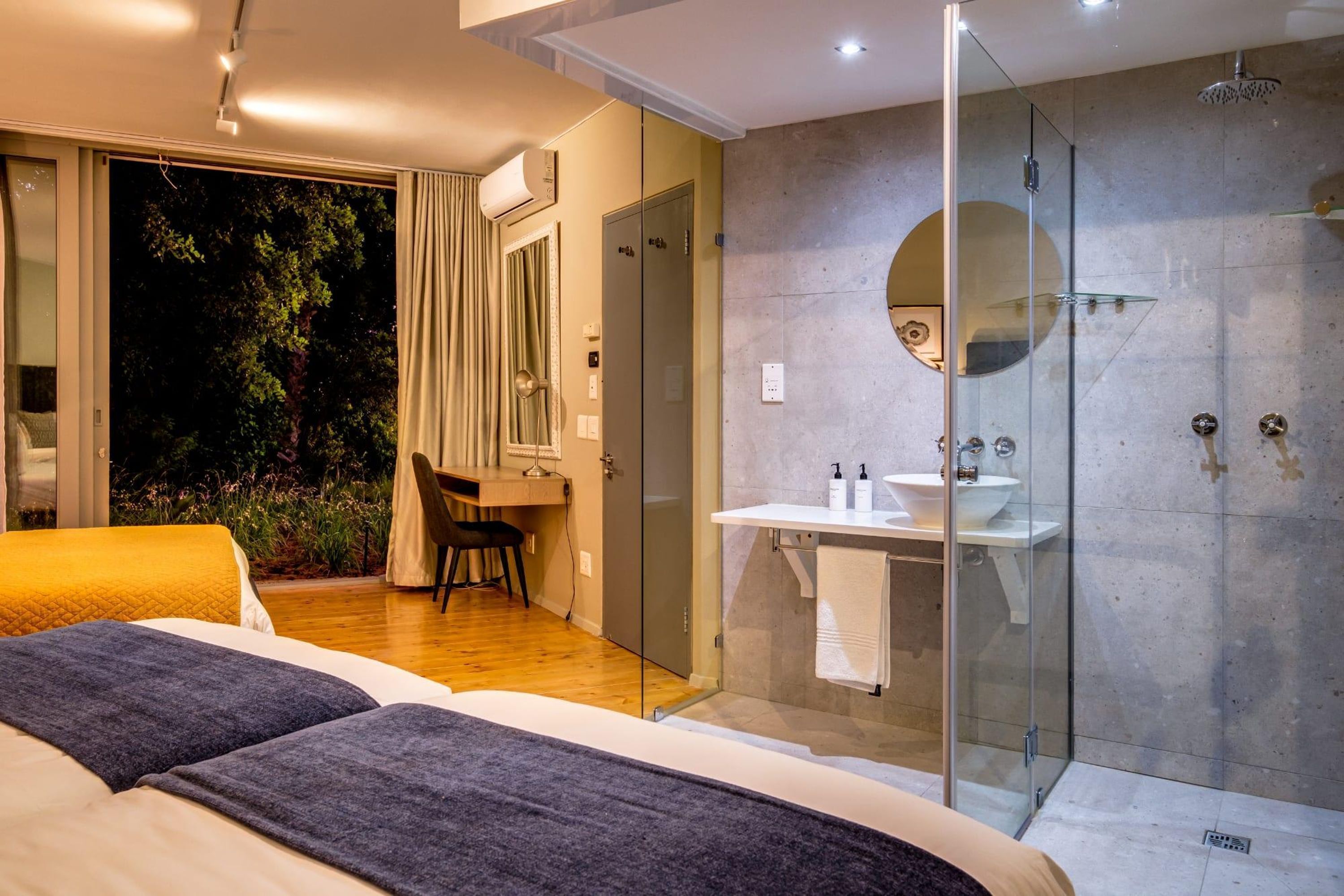 Une chambre à coucher moderne avec un grand lit, une douche en verre et une vue sur l’extérieur.