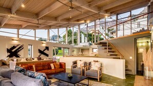 A spacious living area with a large window, a sofa set, a coffee table, and a staircase leading to an upper level. - Unique Villa w Pool Garden and Sea Views Lobster Villa (Cape Town)