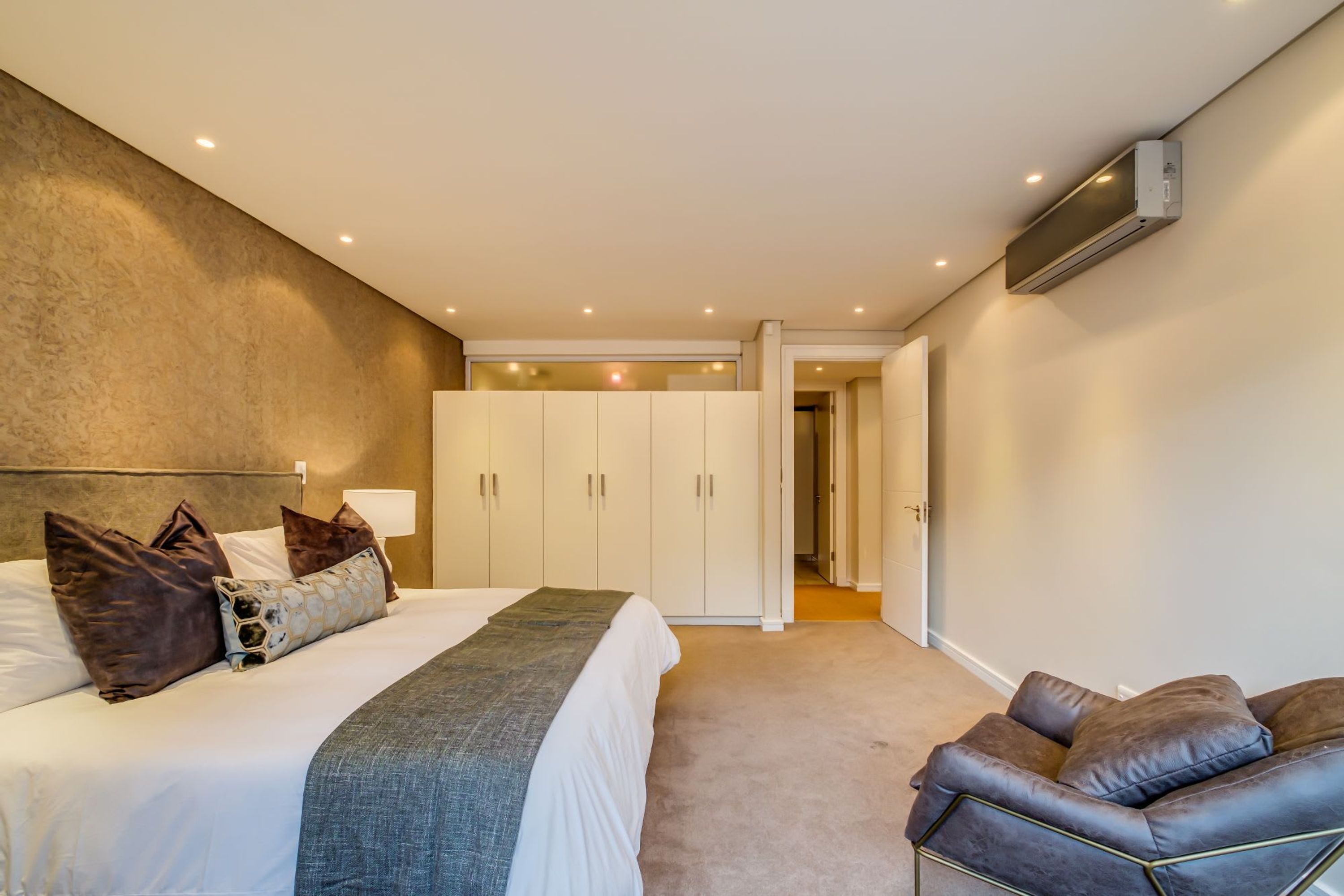 Un dormitorio con cama, armario y zona de estar.