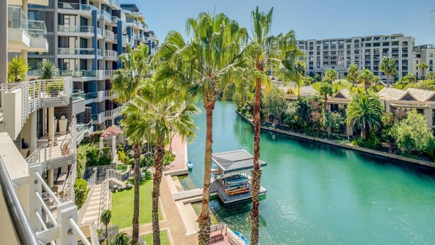 A modern hotel with a river view, outdoor pools, and palm trees. - 308 Juliette on the Waterfront Marina (Cape Town)