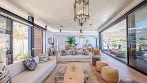 A modern living room with a sofa set, ottomans, and a coffee table. - Spectacular Ocean Villa in Camps Bay (Cape Town)