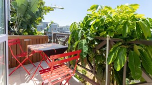 A balcony with a table and chairs, surrounded by lush green plants and a view of buildings. - Unique City View Apartment in De Waterkant 207 DWP (Cape Town)