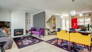 Un vaste espace de vie doté d’une cheminée, d’un canapé, d’une table à manger avec des chaises et d’un escalier menant à un autre niveau.
