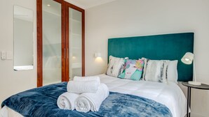 Une chambre d’hôtel avec un grand lit, une tête de lit de couleur turquoise et un miroir.