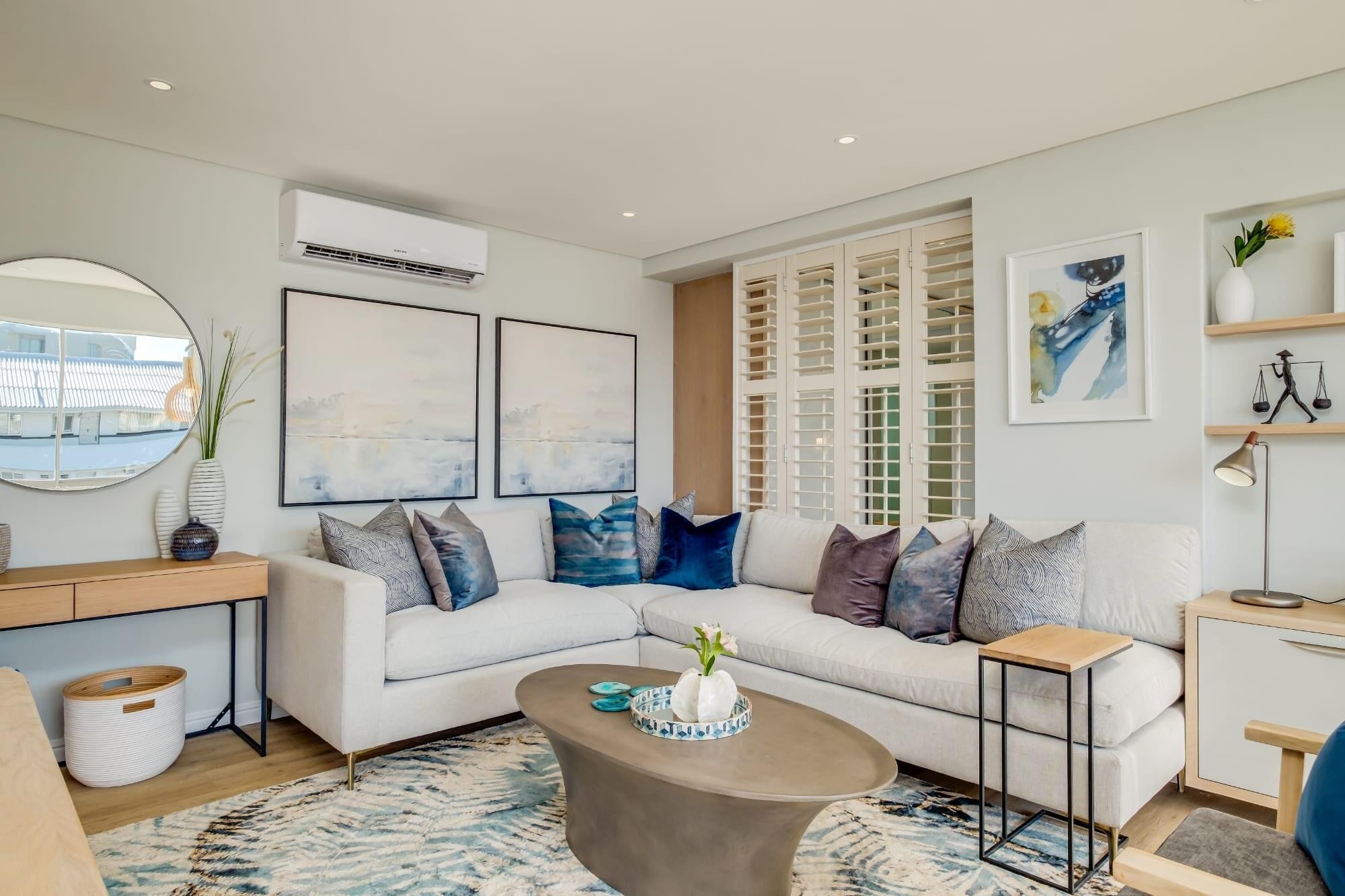 A modern living room with a white sofa, a coffee table, and artwork on the walls.