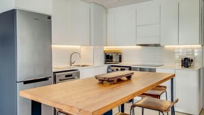 Eine moderne Küche mit weißen Schränken, Edelstahlgeräten und einer Holztischinsel mit Hockern.