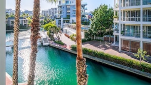 A modern building with a pool and palm trees. - Modern Waterfront Apartment w Canal Views Gulmarn 201 (Cape Town)