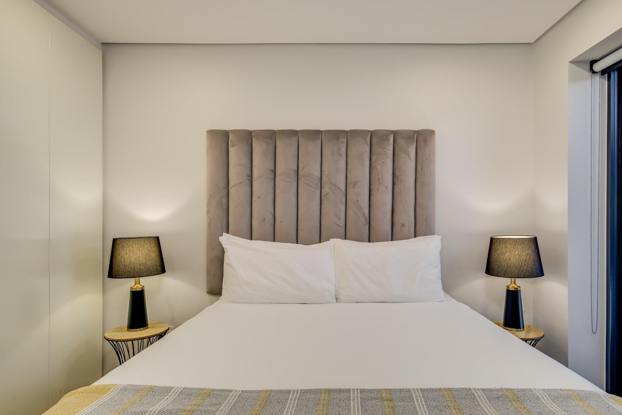 A hotel room with a large bed, two bedside lamps, and a headboard.