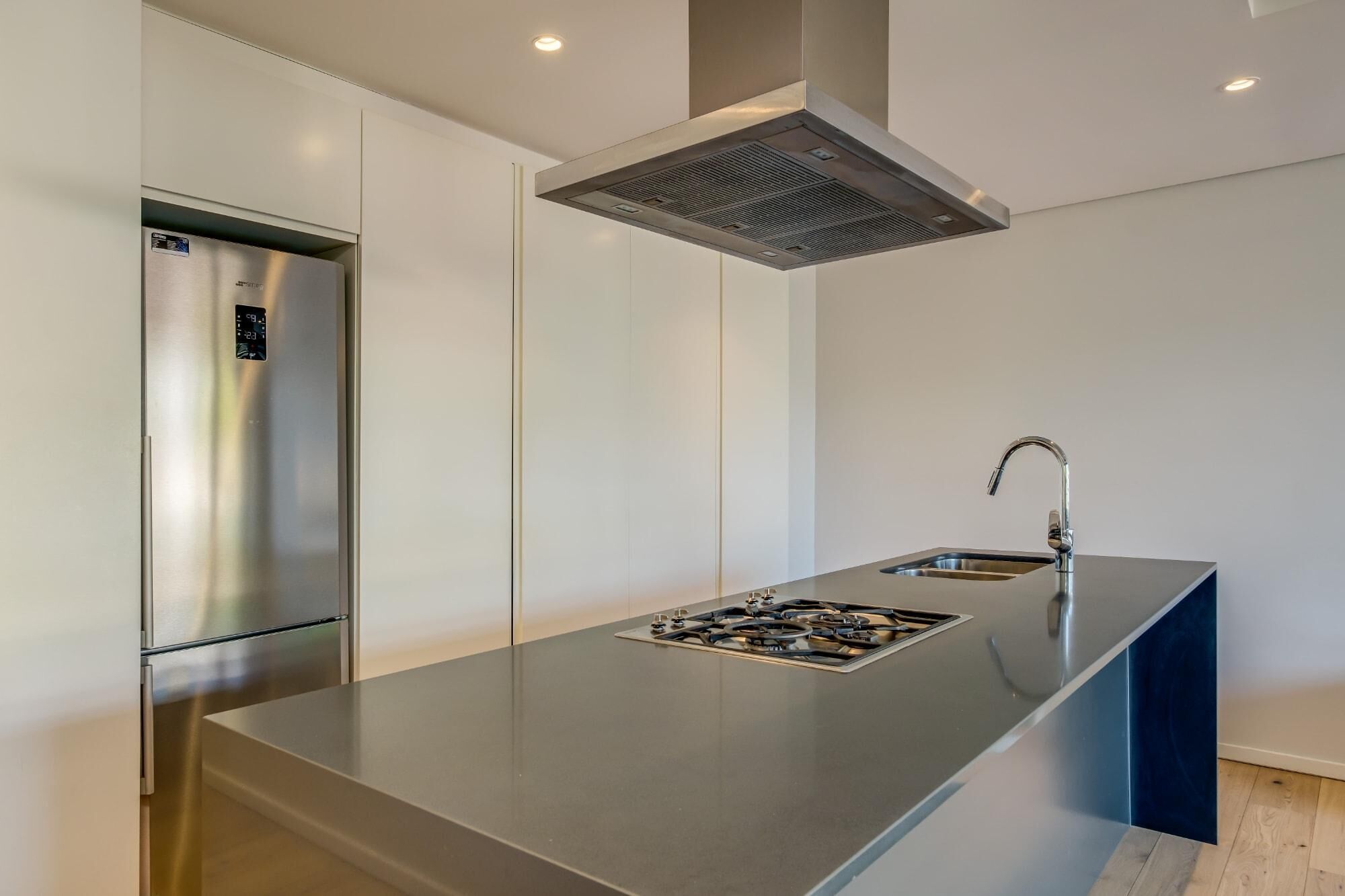 A modern kitchen with a stainless steel refrigerator, a built-in gas stove, and a sleek sink.