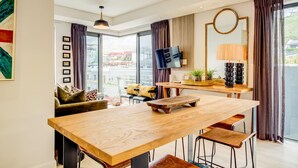 A modern kitchen with a wooden table, bar stools, a TV, and a view of the city. - Gorgeous Apartment in Bustling De Waterkant 304 on N (Cape Town)