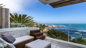 Varanda com vista para o oceano e costa rochosa.