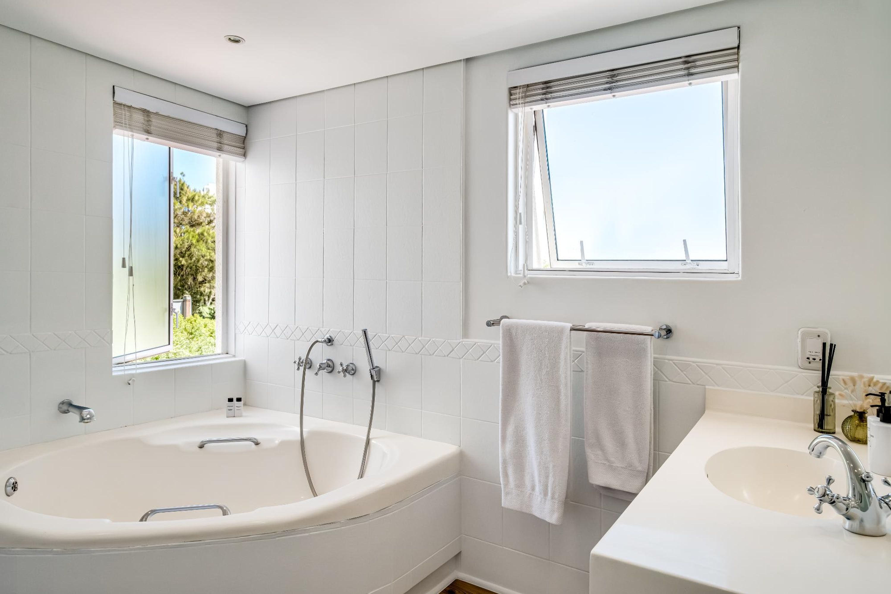 A modern bathroom with a freestanding bathtub, a vanity with a sink, and a window with a view of greenery.