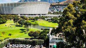 Un grand stade doté d’un toit incurvé, entouré d’un parcours de golf et d’immeubles résidentiels.