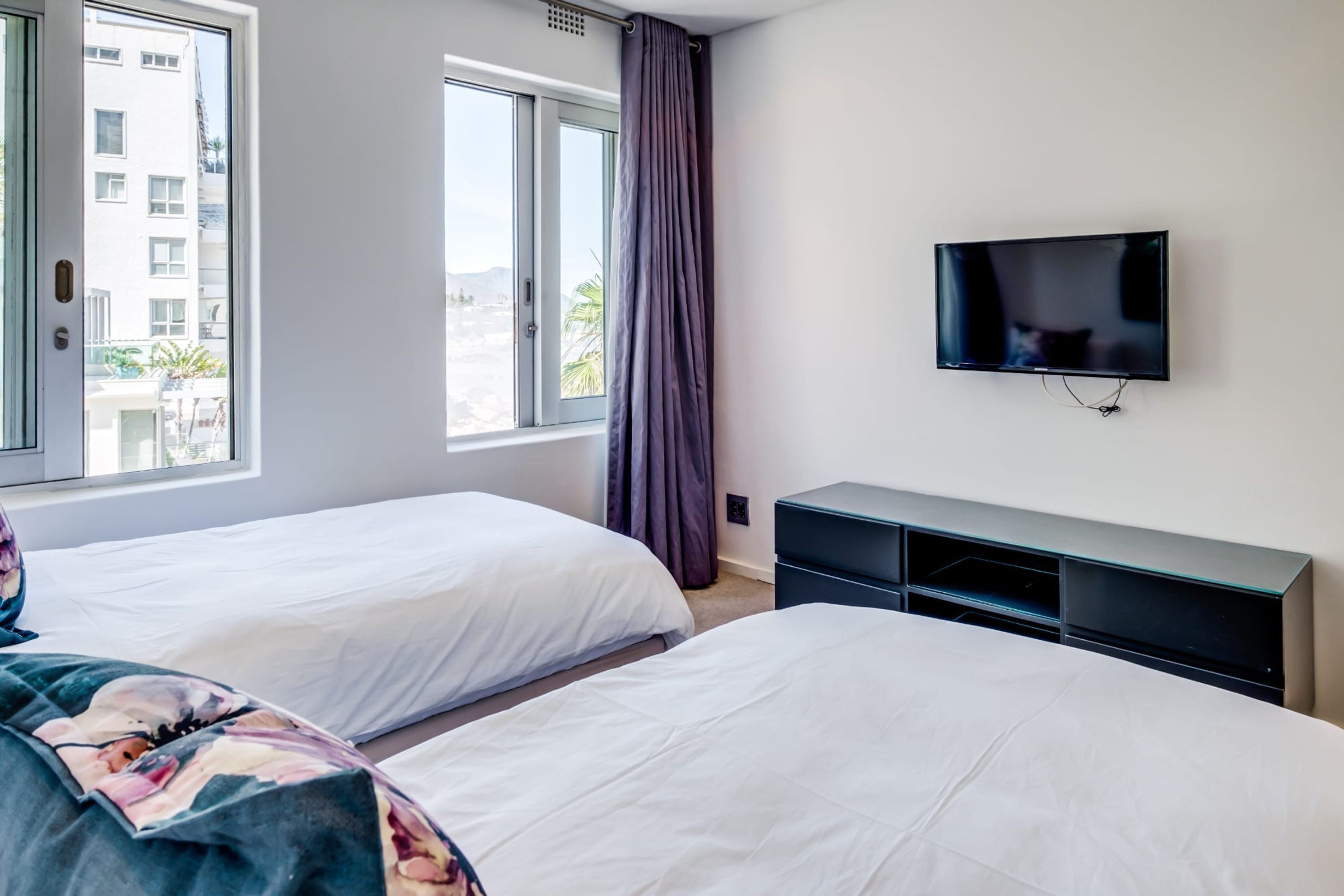 Une chambre d’hôtel avec deux lits, une télévision et une fenêtre avec des rideaux.