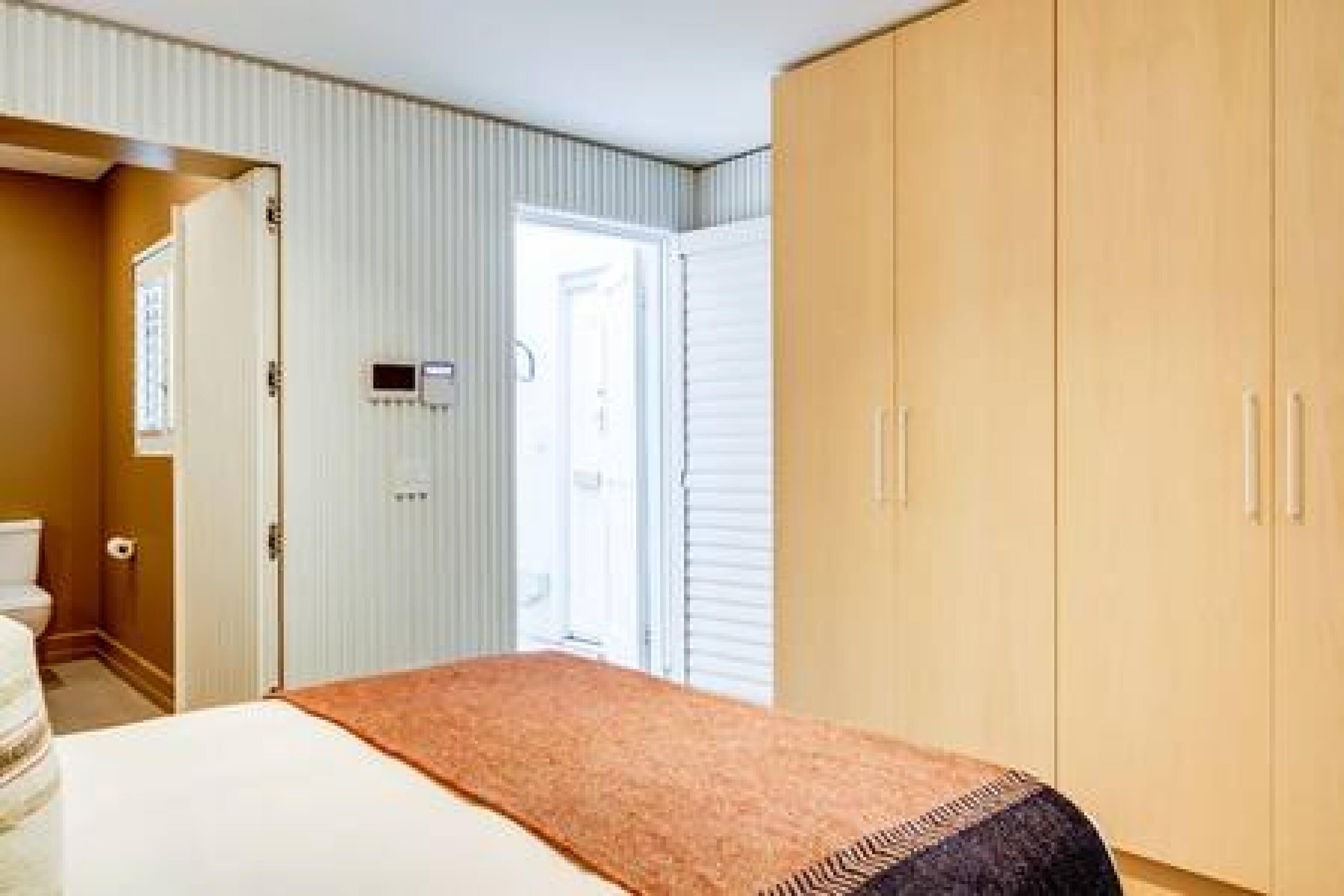 Une chambre à coucher avec un lit, une armoire et une salle de bain visible à travers une porte ouverte.