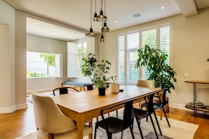 A dining area with a wooden table, black chairs, and potted plants.