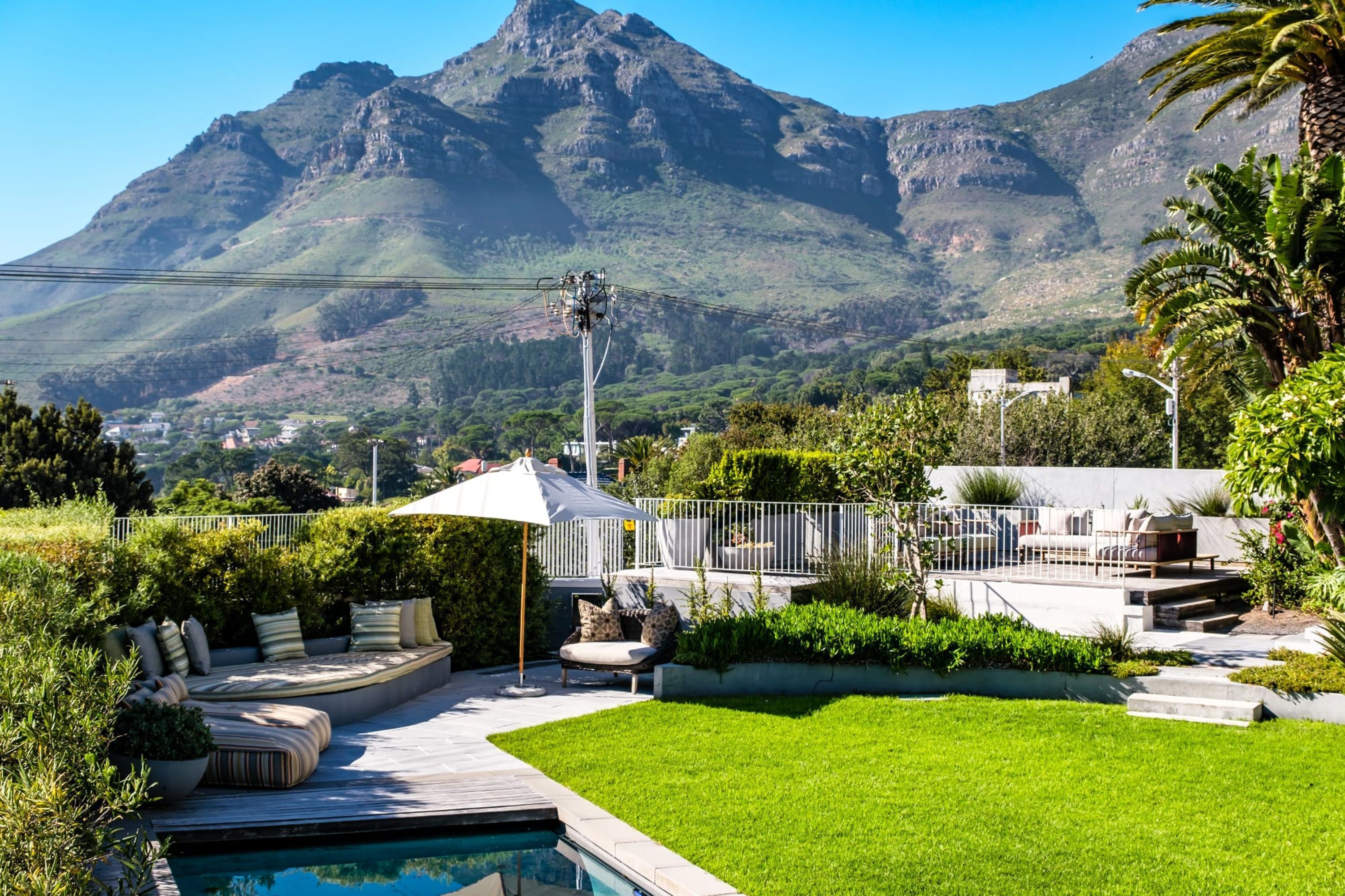 A pool area with a seating arrangement, surrounded by greenery and a view of a mountain.
